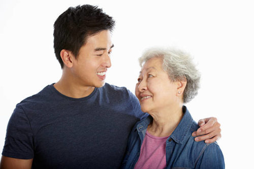 Studio Portrait Of Chinese Mother With Adult Son Smiling To Each Other